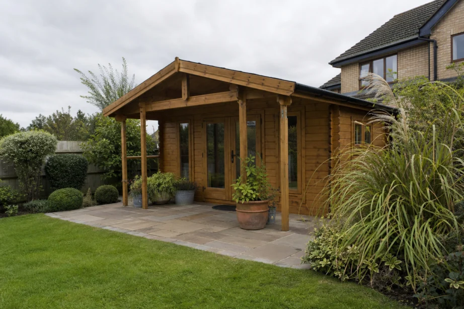 Timber garden log cabin with double doors and patio in a mature UK garden